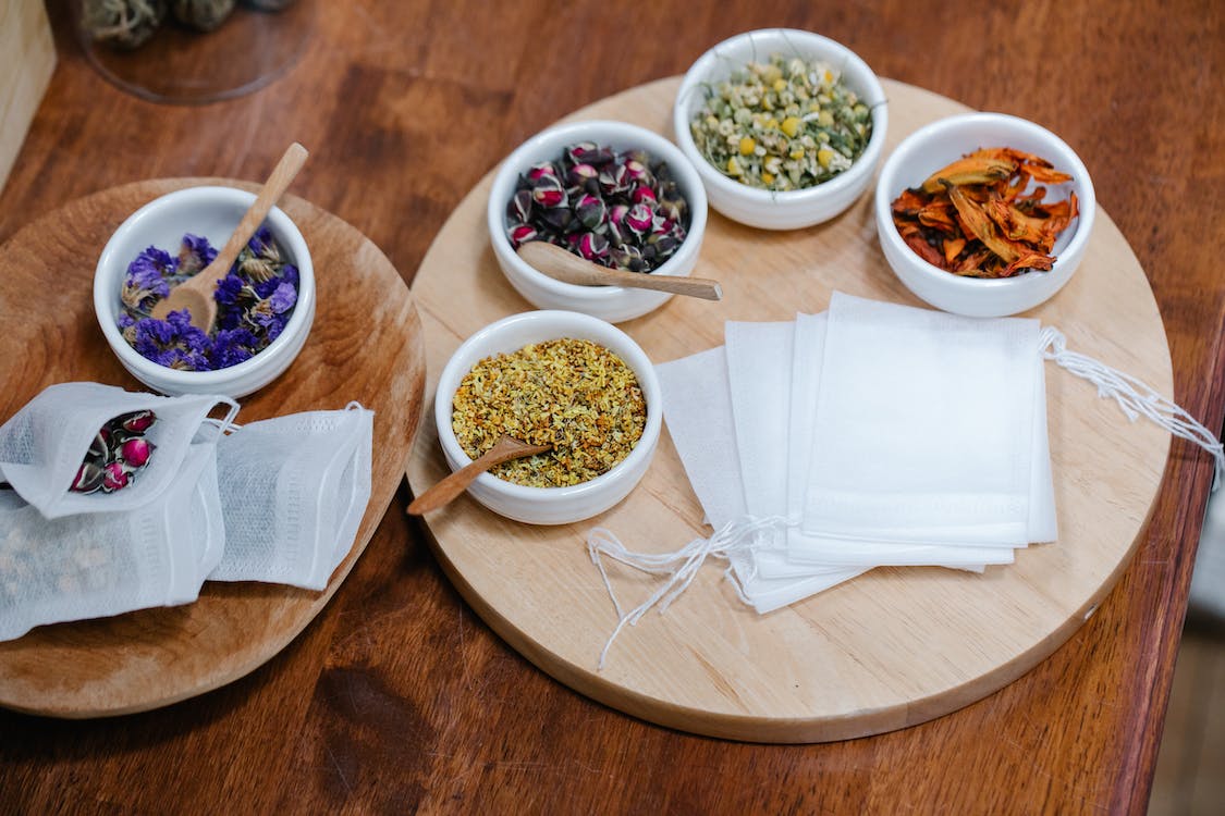 Small bowls of colorful herbs on a wooden tray